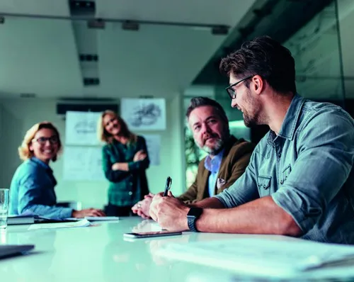 Imagen de una mujer joven sonriendo al salir de una junta con el equipo de gerencia de mercadeo.
